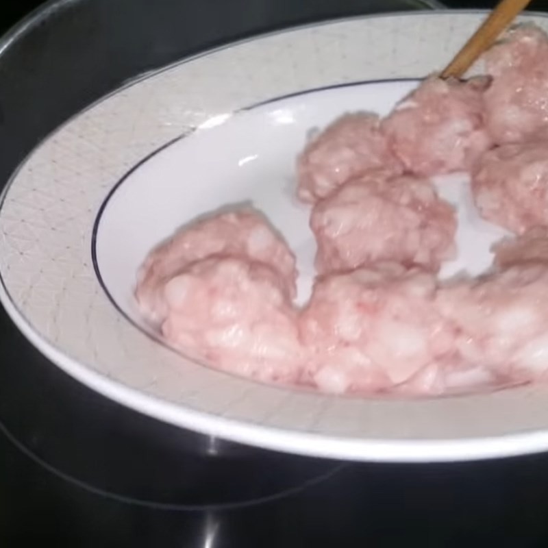 Cho thịt viên và cà chua vào nồi nước sôi để nấu canh
