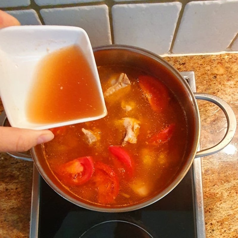 Thêm dấm bỗng và nêm nếm gia vị cho canh chua sườn
