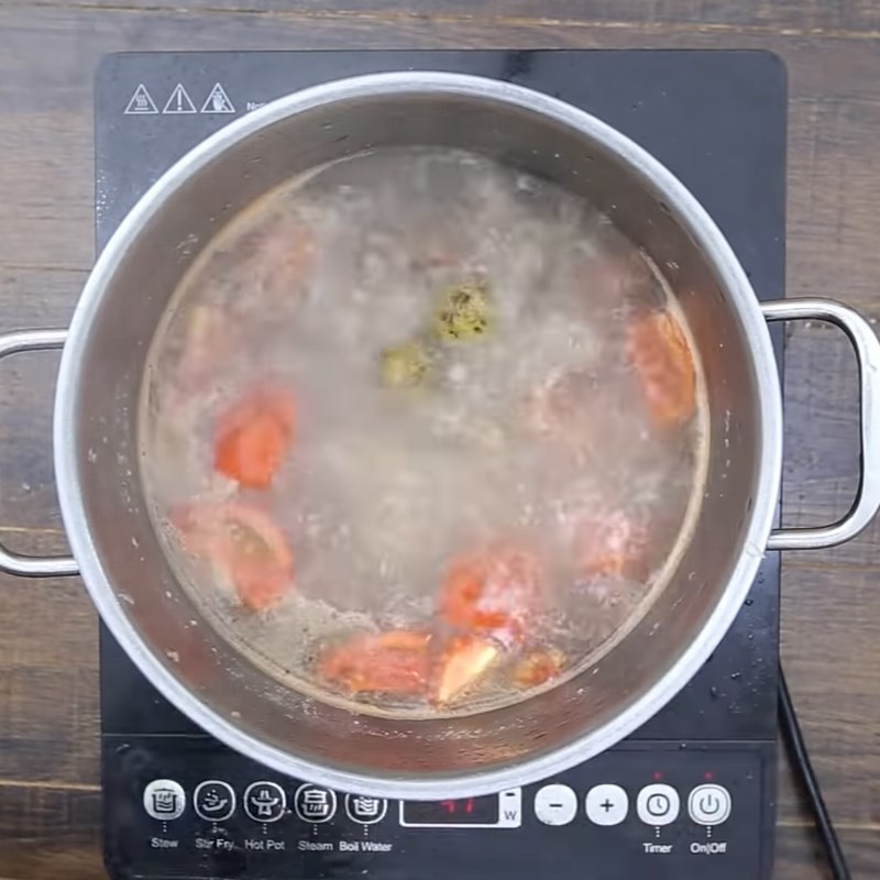 Thêm hành lá tươi vào canh sấu nấu sườn trước khi tắt bếp