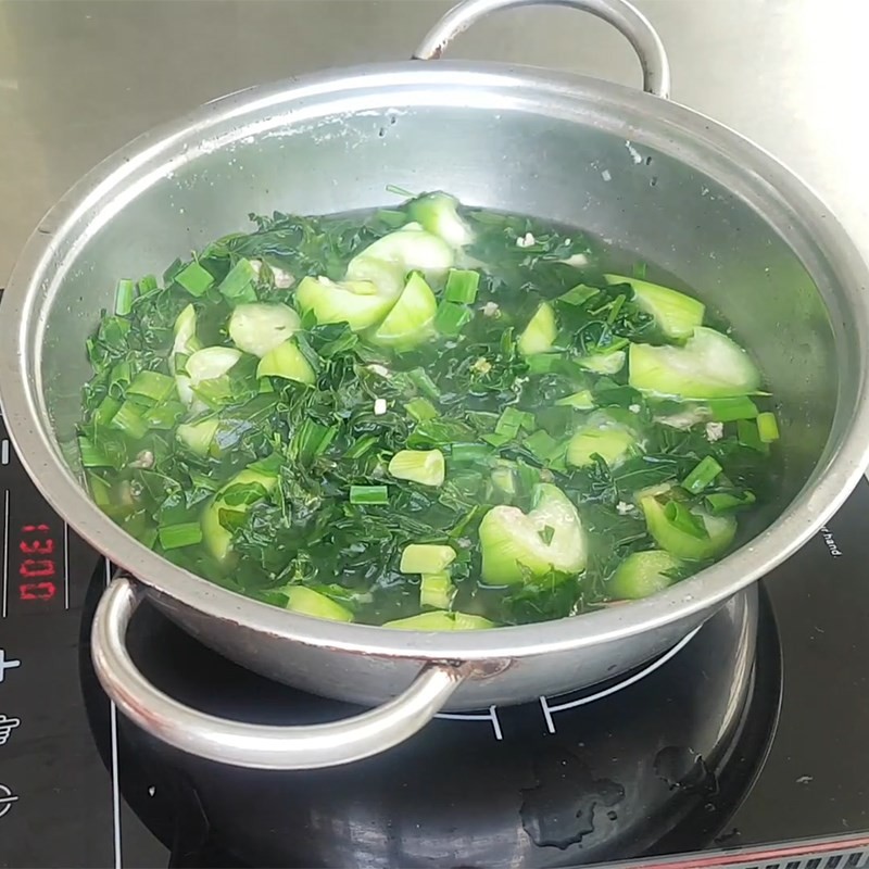 Hành lá và gia vị cuối cùng được thêm vào nồi canh rau ngót với mướp thịt bằm trước khi tắt bếp