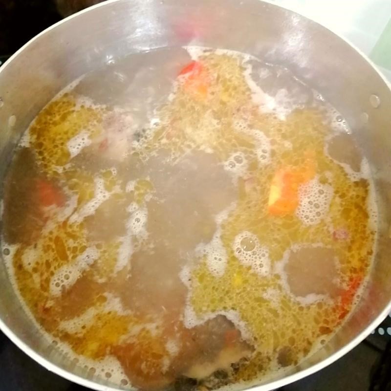 Thêm các loại rau củ và nước me vào nồi canh đầu cá thu đang sôi