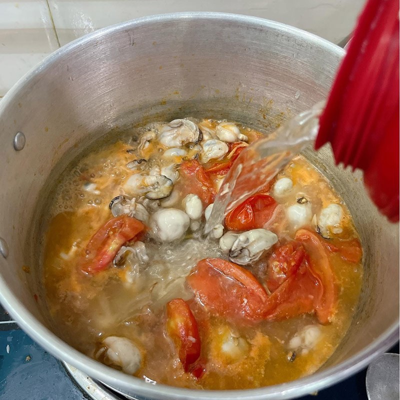 Nồi canh hàu lá lốt đang sôi nhẹ, lá lốt vừa được thêm vào tạo hương thơm đặc trưng
