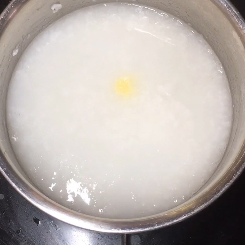 Cho gạo đã trộn dầu vào nồi cùng nước để bắt đầu nấu cháo hàu đậu xanh