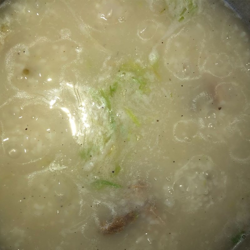 Khuấy đều cháo trong nồi sau khi thêm gia vị và hành tiêu giã nhuyễn