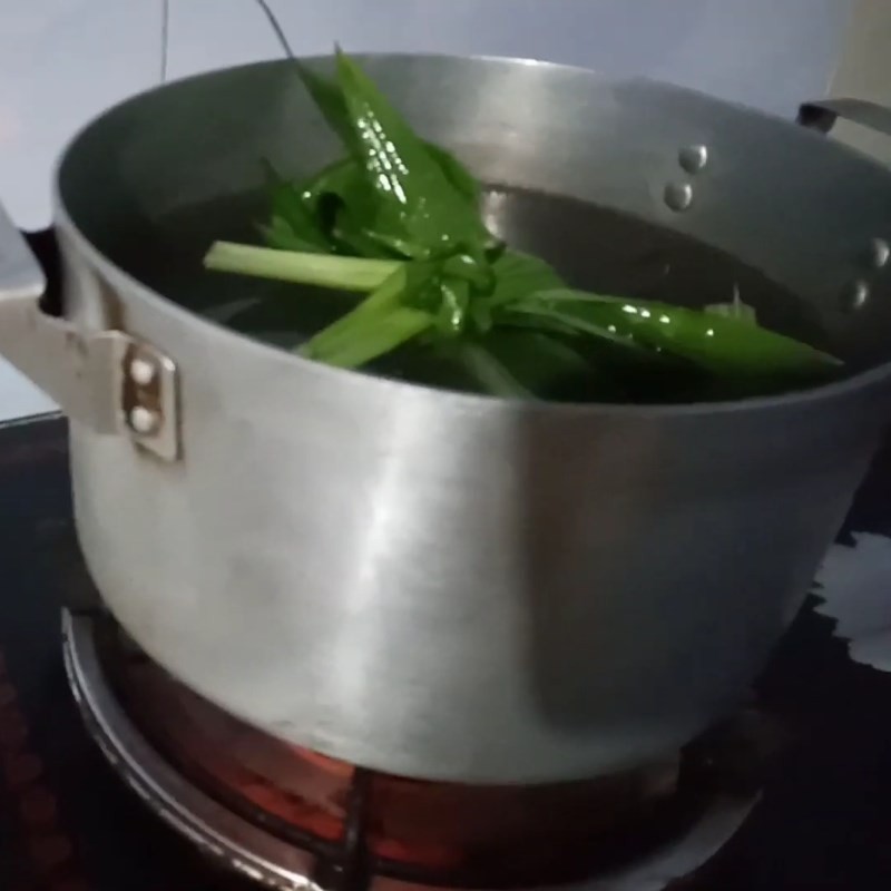 Nồi nước đường phèn với lá dứa đang sôi, tạo nền cho chè hạt mít