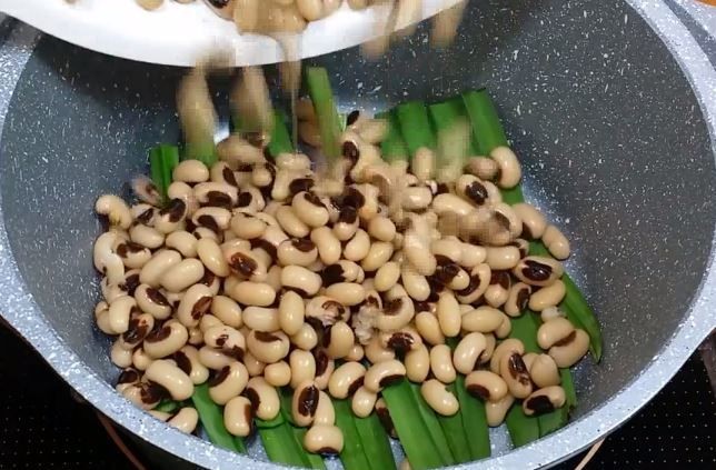 Đậu trắng đã sơ chế được xếp đều lên lớp lá dứa để nấu chè