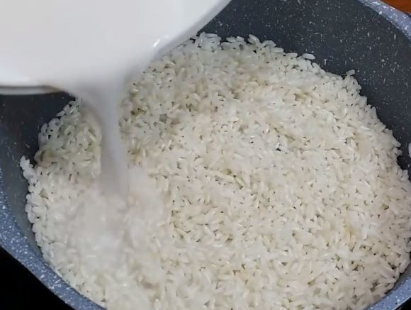 Rưới đều nước cốt dừa và nước lọc vào nồi chè đậu trắng cúng đầy tháng