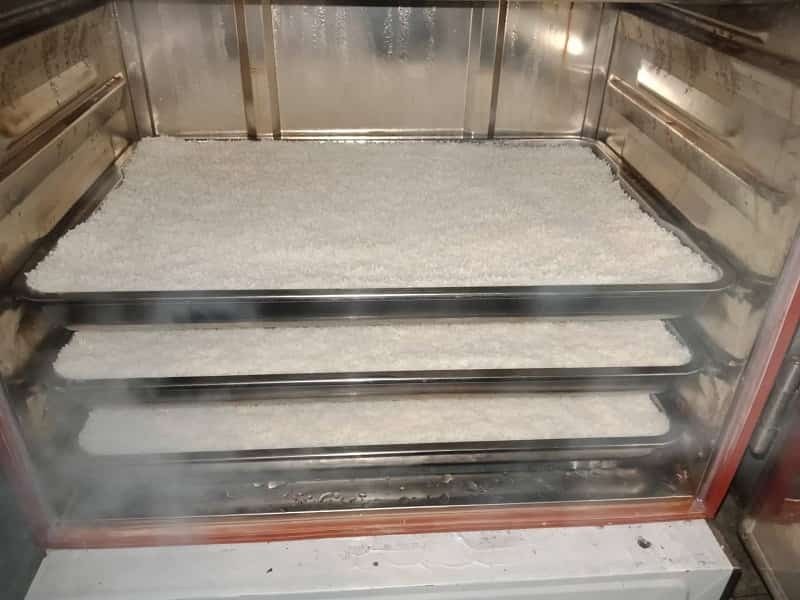Cơm gạo đang được nấu chín trong tủ hấp công nghiệp để chuẩn bị ủ men rượu