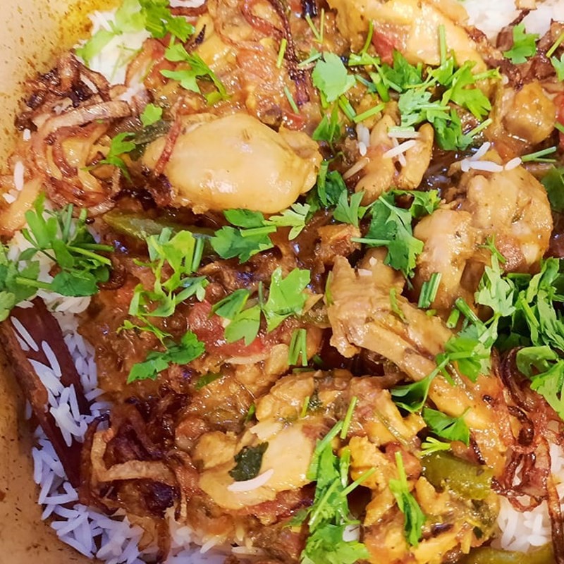 Hình ảnh cơm và gà được xếp lớp trong nồi, chuẩn bị cho quá trình hầm Biryani, một bước quan trọng trong cách nấu cơm Ấn Độ