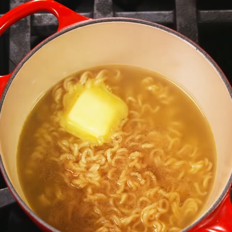 Thêm gia vị, bơ và bột tỏi vào nồi mì đang sôi, làm phong phú cách nấu mì với tôm