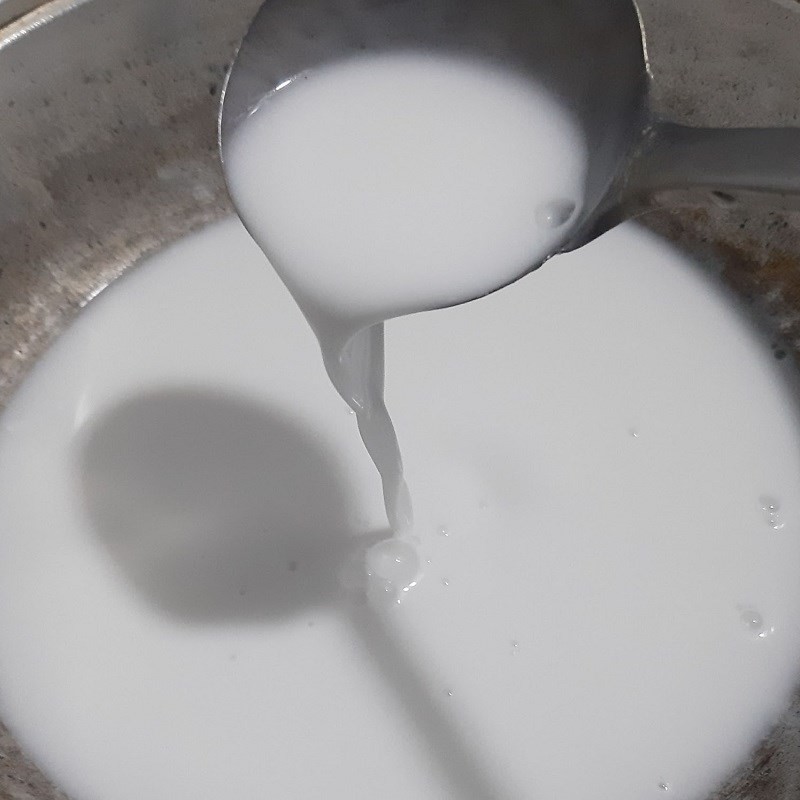 Nước cốt dừa sánh mịn đang được khuấy đều trên bếp, chuẩn bị hoàn thành cho món chè bí đỏ nước cốt dừa