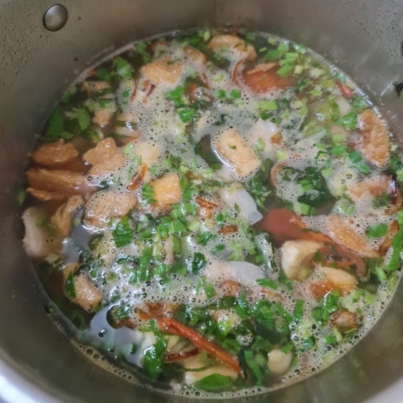 Hoàn thiện nước dùng bún ốc sườn với rau thơm và gia vị