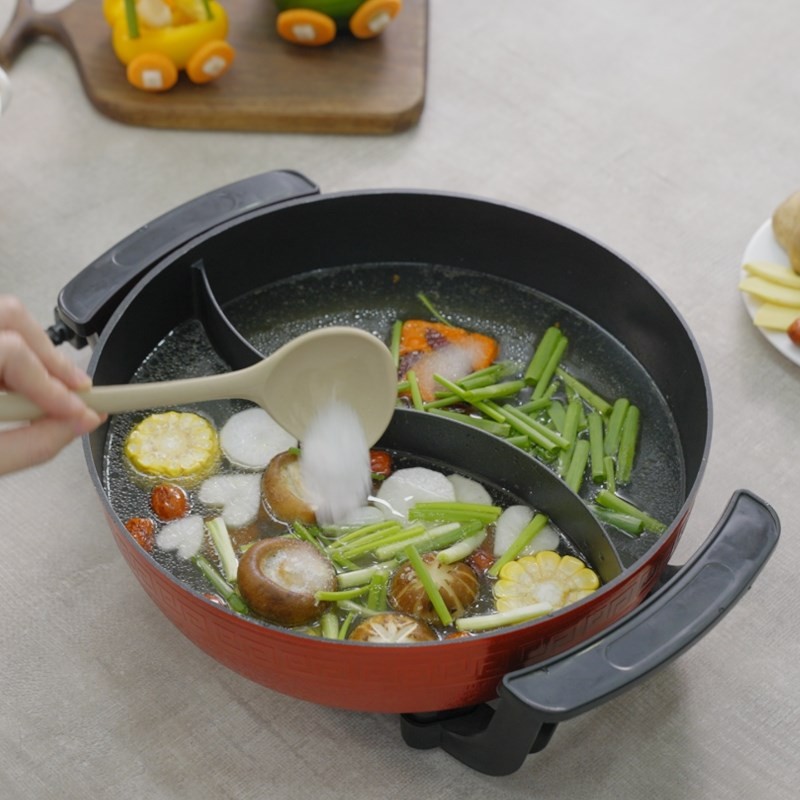 Đảo đều gia vị trong nồi lẩu uyên ương để nước dùng hòa quyện