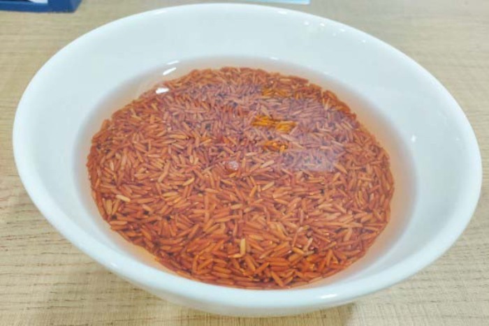 Bát gạo lứt đang được ngâm trong nước, chuẩn bị cho quá trình nấu cháo gạo lứt bằng nồi cơm điện
