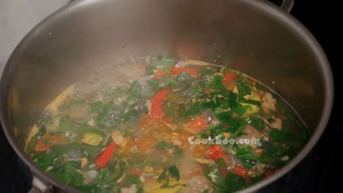 Nồi canh trùng trục lá lốt đang sôi nhẹ trên bếp, tỏa hương thơm nức mũi, chuẩn bị hoàn thành