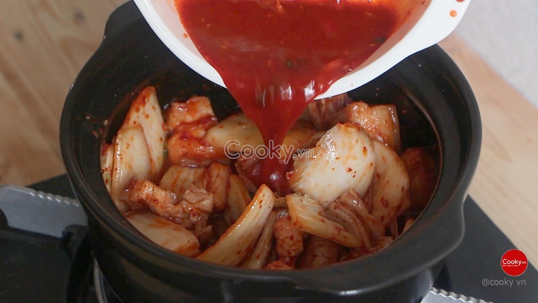 Kim chi và nước dùng đã được thêm vào nồi thịt ba chỉ, tạo nền tảng hương vị cho món canh kim chi