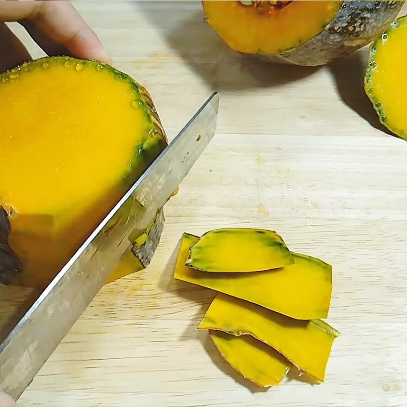 Cắt bí đỏ thành miếng vừa ăn, chuẩn bị cho món cà ri bí đỏ chay đậm đà