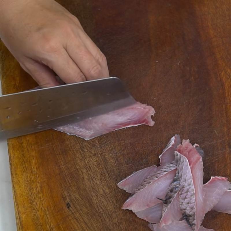 Rửa sạch đầu và xương cá lóc để nấu nước dùng bánh canh