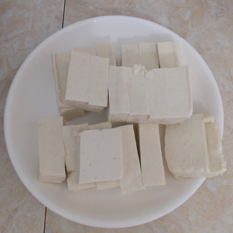 Cắt đậu hũ trắng thành miếng vừa ăn để chuẩn bị nấu canh mồng tơi chay