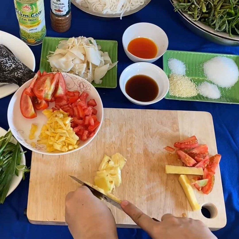 Thái thơm và cà chua để chuẩn bị nước lẩu cá mú măng chua
