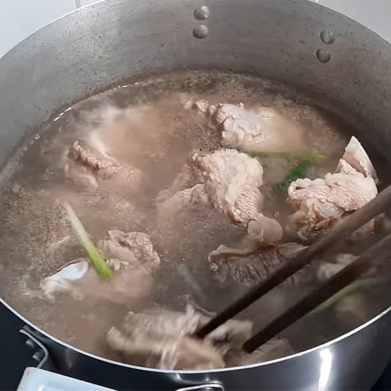 Sườn bò được chần qua nước sôi với gừng và hành để khử mùi, bước quan trọng trong cách nấu sườn bò hầm.