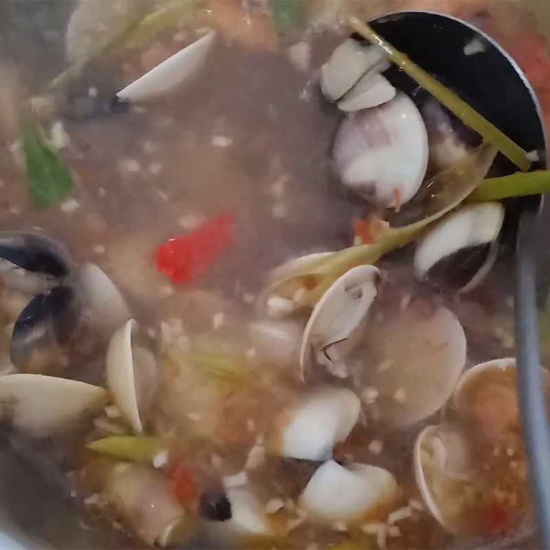 Nồi lẩu nghêu chua cay đã hoàn thành với màu sắc hấp dẫn và hương thơm nồng nàn, sẵn sàng để thưởng thức cùng bún và rau tươi