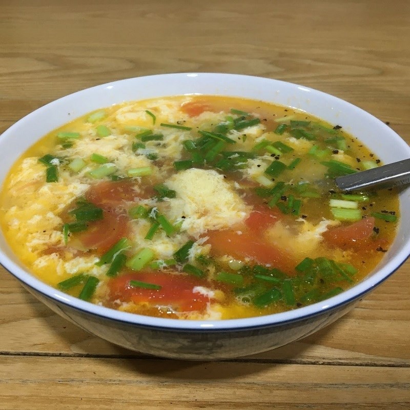 Một tô canh cà chua trứng nóng hổi, rắc hành lá và tiêu, sẵn sàng thưởng thức