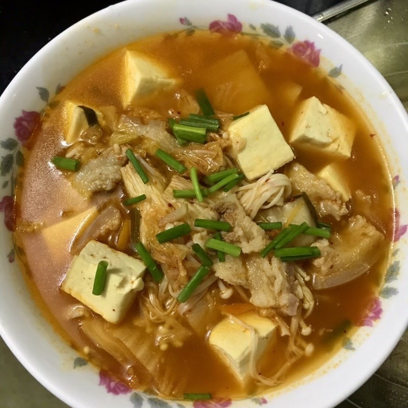 Cận cảnh tô canh kim chi thịt heo với đậu hũ, nấm kim châm và thịt, thể hiện một cách nấu canh kim chi đơn giản nhưng đầy đủ dinh dưỡng.