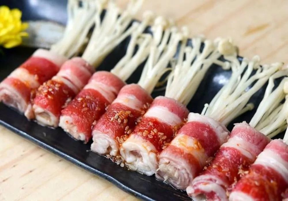 Những cuộn thịt bò ba chỉ mềm mọng bọc nấm kim châm trắng nõn, nướng vàng đều, hấp dẫn với sốt Hàn Quốc đặc trưng