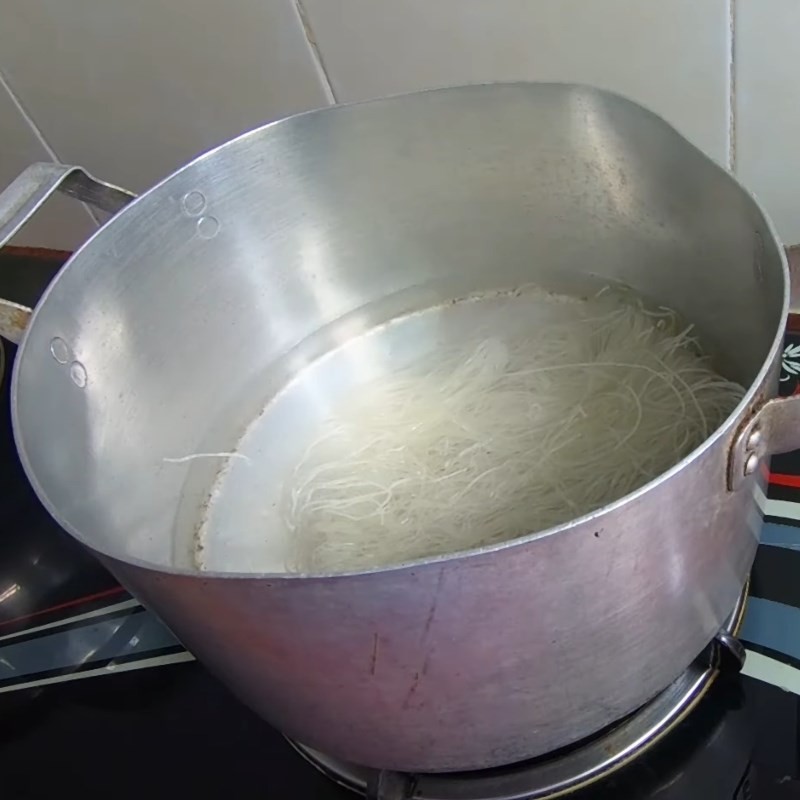 Trụng bún gạo khô trong nước sôi, làm mềm sợi bún cho món bún thịt cà chua