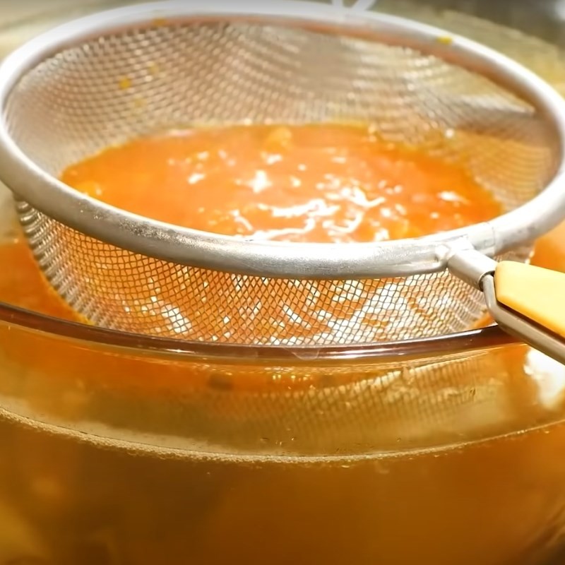 Hỗn hợp cà chua đã xào được lọc qua rây vào nồi nước canh cá, tạo màu sắc hấp dẫn
