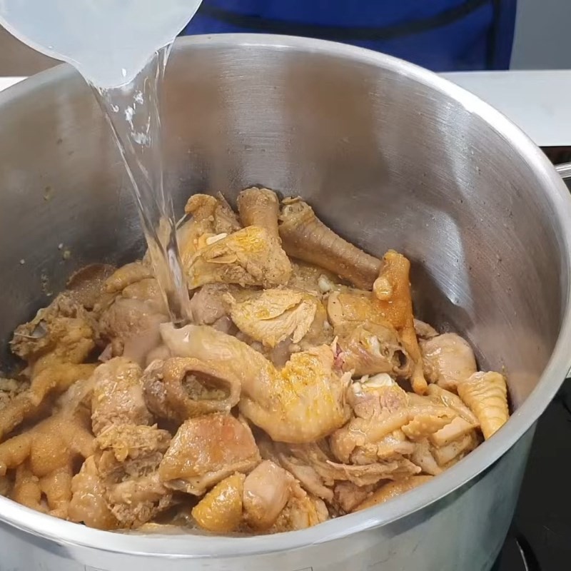 Thêm nước dừa tươi và nước lọc vào nồi gà đang xào