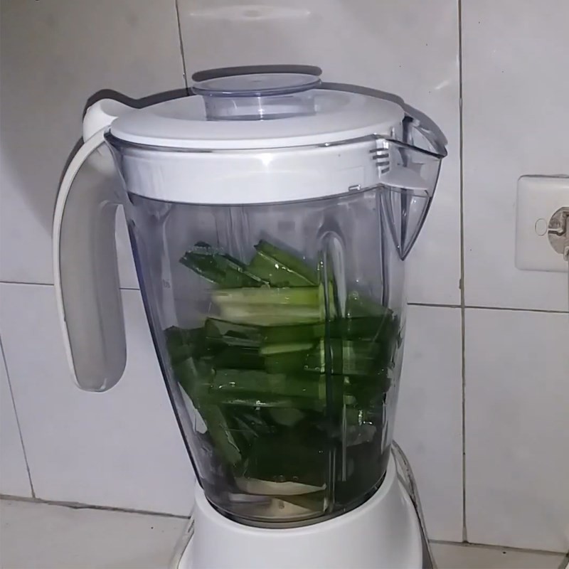 Bước 1 trong cách nấu chè cốm ngon Hà Nội: Xay lá dứa tươi để lấy nước cốt tạo màu và hương thơm tự nhiên.