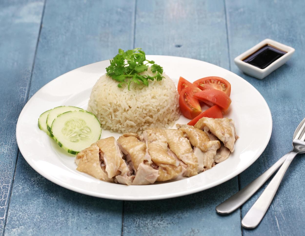 Món cơm gà nóng hổi kèm rau sống và dưa chuột.