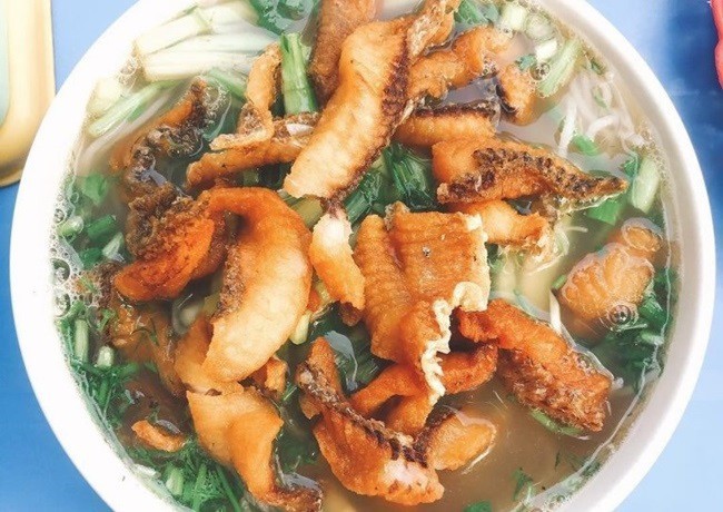 Tô bún cá Hà Nội đầy đủ các loại topping như cá chiên, đậu hũ, rau thơm và nước dùng chua thanh, sẵn sàng để thưởng thức
