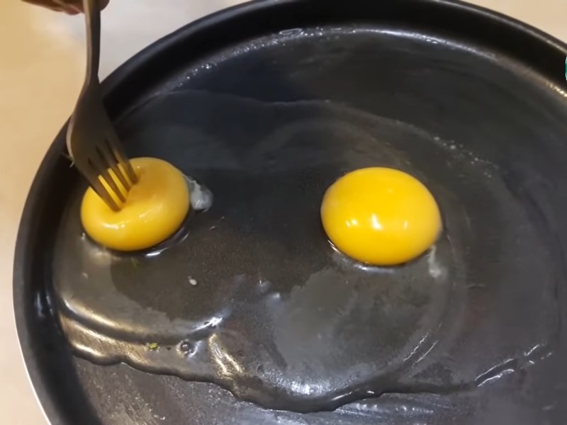 Dùng nĩa đâm lòng đỏ trứng để chiên bằng lò vi sóng
