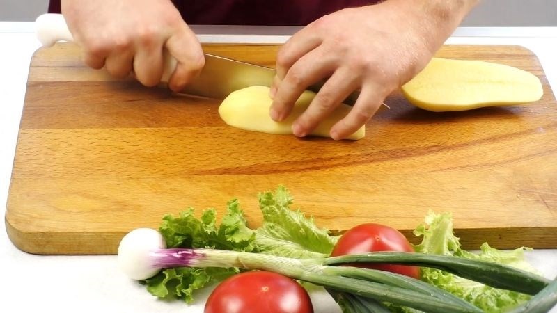 Bổ đôi củ khoai tây và cắt thành miếng dày, chuẩn bị thái hạt lựu