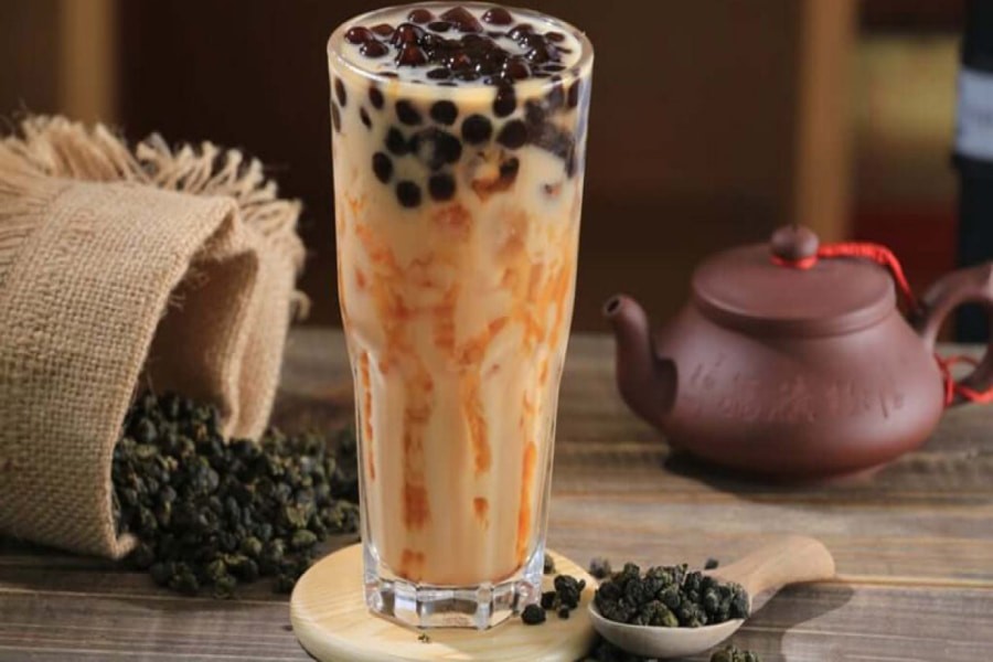 Các loại nguyên liệu cơ bản để pha chế trà sữa truyền thống bao gồm trà, sữa bột, đường và trân châu đen, được sắp xếp gọn gàng trên bàn bếp