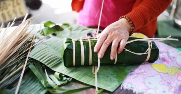 Hoàn thành công đoạn gói bánh tét, buộc chặt bằng lạt tre để giữ hình dáng