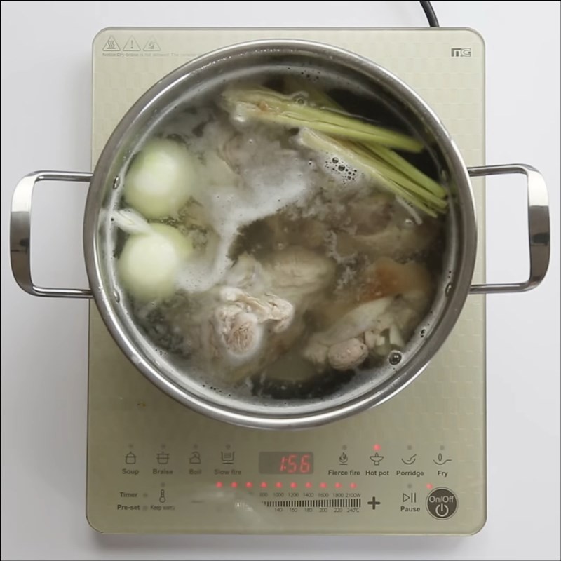 Nồi nước dùng chân giò đang được hầm cùng sả và hành tây, tạo nên hương vị ngọt thanh cho cách nấu bún bò Đà Lạt.