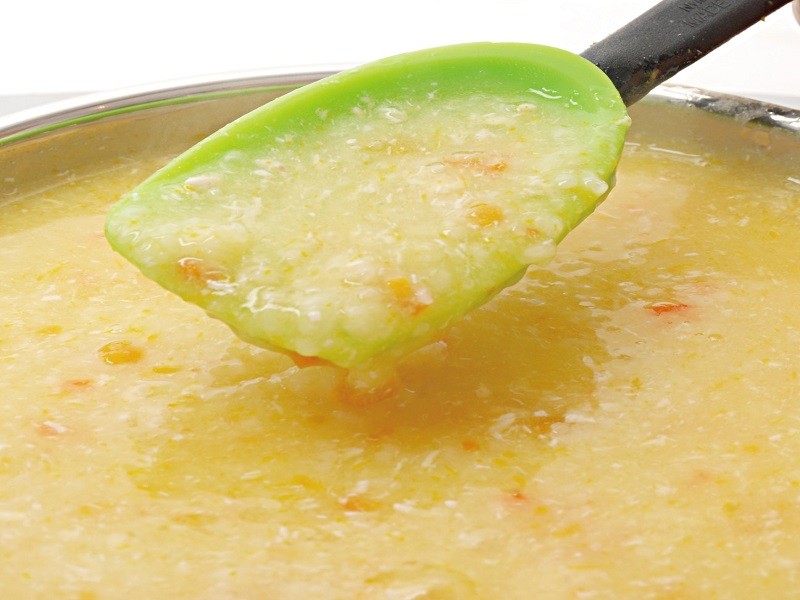 Trộn thịt gà và bí đỏ vào cháo đang nấu cho bé
