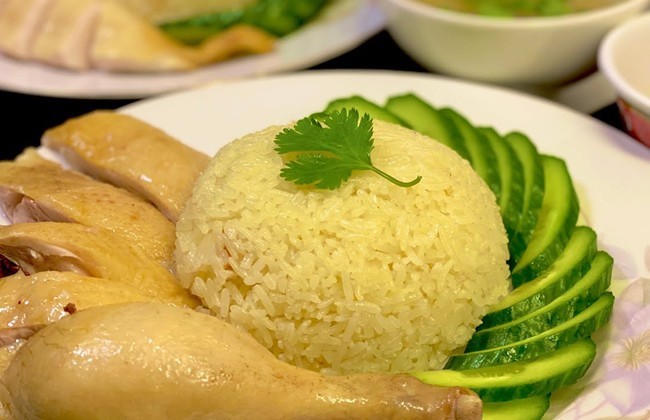 Đĩa cơm gà Hải Nam hoàn chỉnh với thịt gà chặt miếng, cơm vàng ươm và dưa chuột thái lát