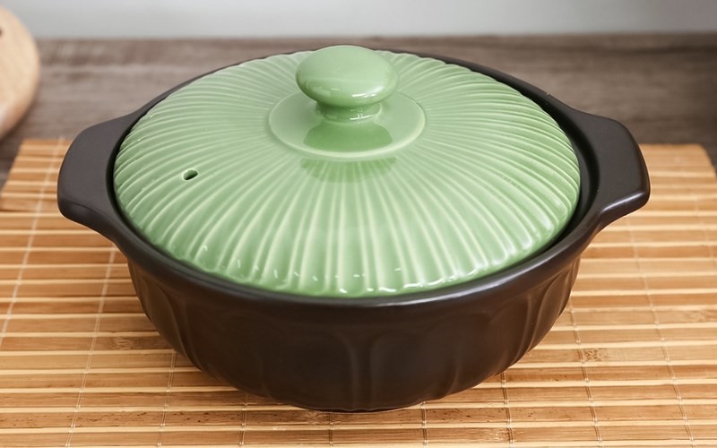 Chiếc nồi đất nhỏ gọn với nắp sứ và họa tiết hoa sen, lý tưởng để nấu cơm gạo lứt cho gia đình nhỏ