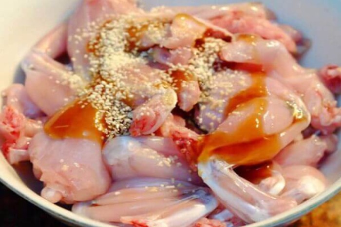 Thịt ếch đang được ướp với các loại gia vị như gừng, tỏi, hành tím, bột nghệ, nước mắm và hạt nêm để chuẩn bị cho món ếch xào măng chua đậm đà.