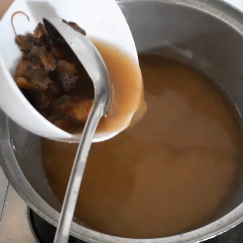 Đổ nước cốt me vào nồi nước sôi để làm canh chua khô cá lóc