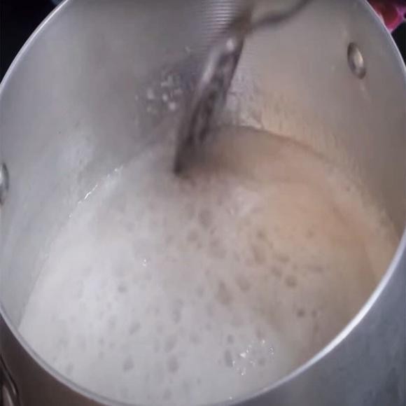 Nồi nước cốt dừa đang được nấu sôi, khuấy đều để bột bắp tạo độ sánh mịn cho phần nước cốt ăn kèm