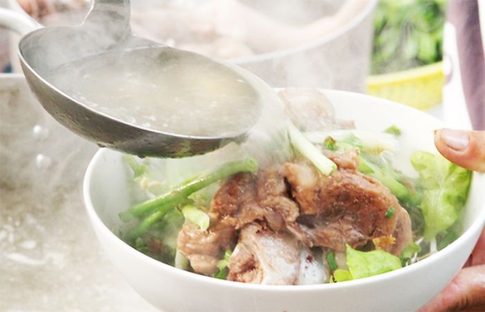 Chan nước lèo nóng hổi vào tô hủ tiếu miền Tây khi phục vụ thực khách