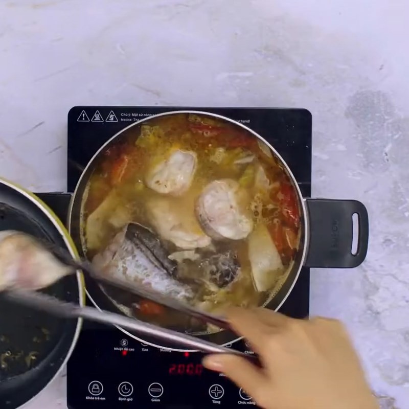 Thêm cá lăng vào nồi canh măng chua đang sôi