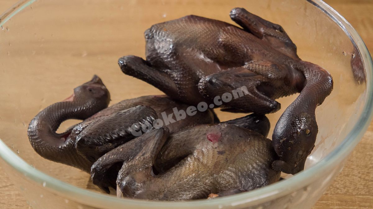 Sơ chế gà ác bằng cách nướng xém da trước khi hầm, bí quyết để món gà với ngải cứu thơm ngon hơn