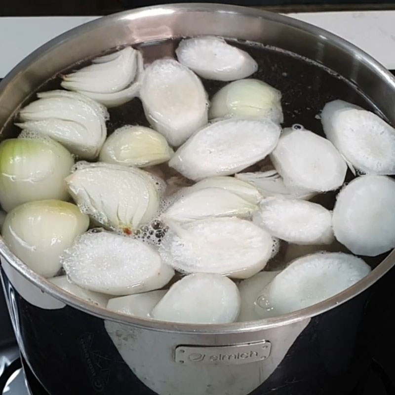 Nồi nước dùng đang được hầm cùng xương heo, củ cải và hành tây